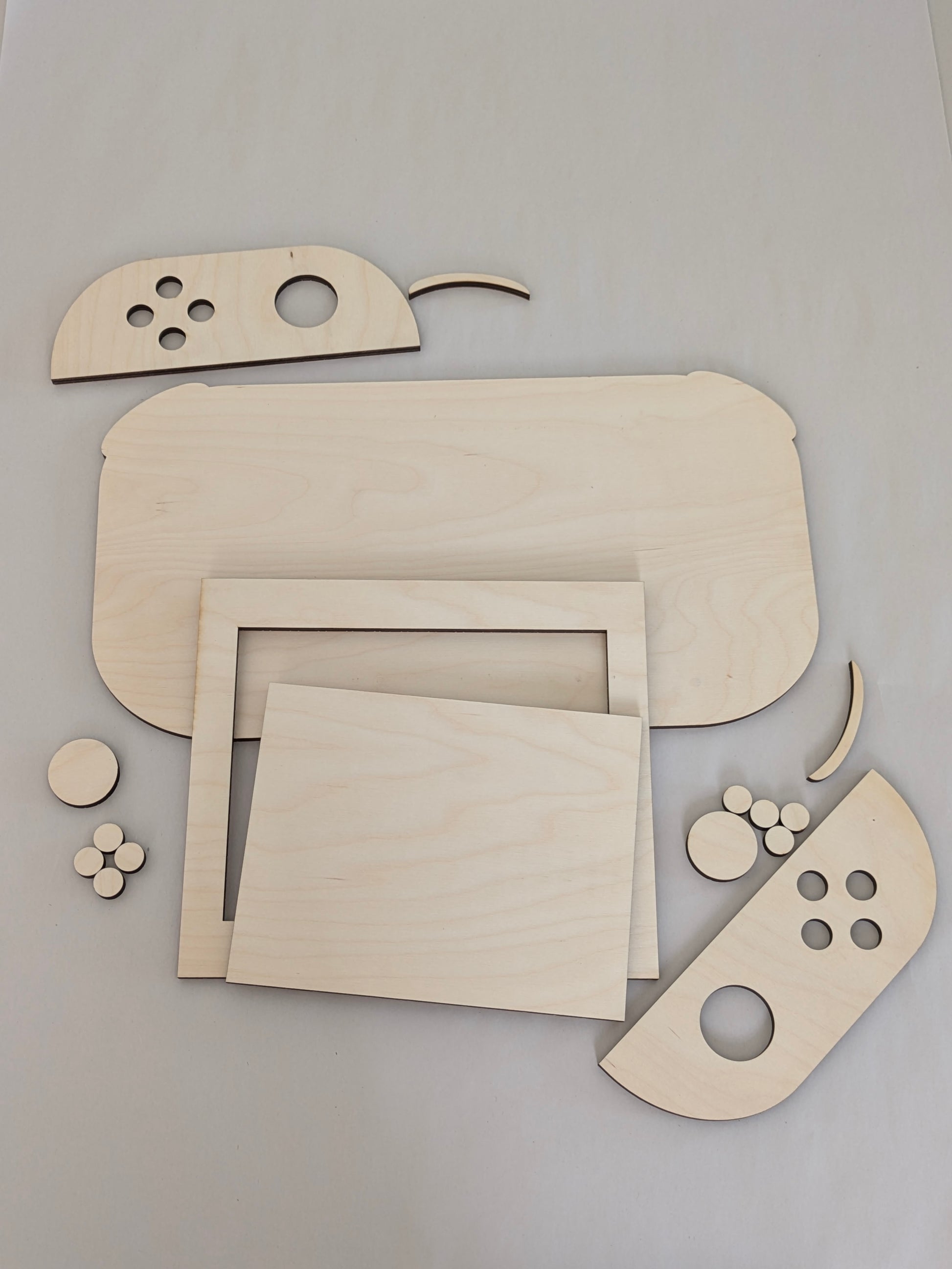 unfinished baltic birch plywood art of a switch gaming console all of the pieces are scattered around showing them off around the scene.